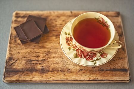 on a wooden stand is a beautiful Cup of tea on a saucer with the image of roses on the background of...
