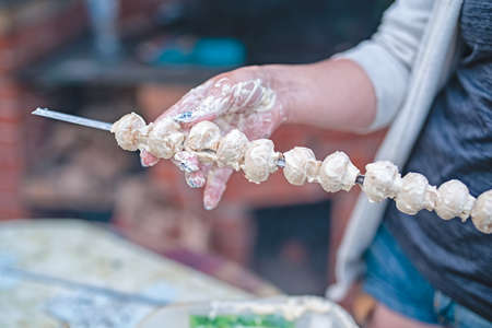 The girl's hands hold mushrooms on the background of the grill. Vegetarianism.の写真素材