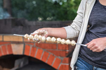 The girl's hands hold mushrooms on the background of the grill. Vegetarianism.の写真素材