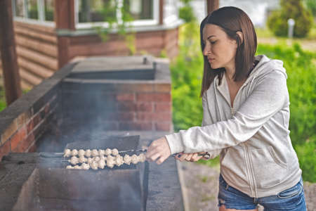 A woman prepares mushrooms on the grill. Vegetarianism.の写真素材