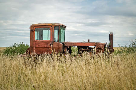 an old abandoned tractor in a field overgrown with tall grass. Natural daylightの写真素材