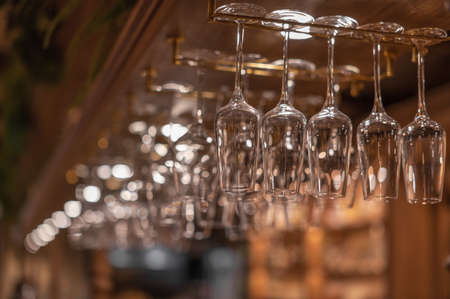 Glasses for alcoholic beverages are suspended above the bar. Close up.の写真素材