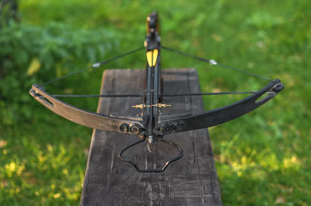 Loaded crossbow on a wooden bench. Selective focus, natural lightの写真素材