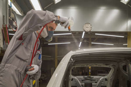 Employee in the shop painting the car body produces coloration of the elementの写真素材