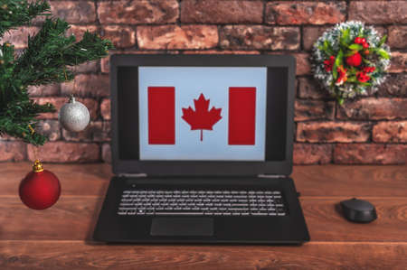 Christmas, new year's composition. Branches of the tree are decorated with Christmas balls on the background of a laptop with the image of the flag of Canadaの写真素材