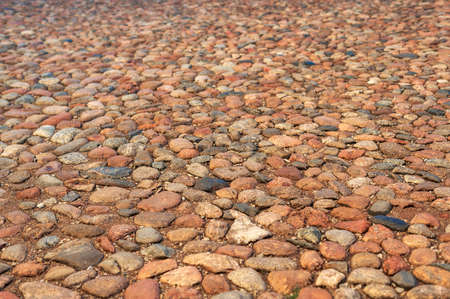 Stone road of stones of different colors, natural light. Close-up.