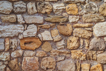 Ancient stone wall made of stones of different colors, natural lighting.
