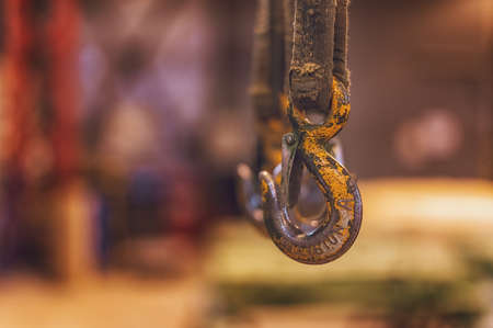 Old yellow frayed hooks of a mobile crane on a blurred background of industrial premises.の写真素材