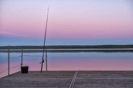 The bottom fishing rod stands with a stretched line against the background of the evening sky. Natural lightの写真素材