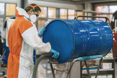 A worker in a paint shop, polishing a blue barrel. Preparation for painting. Production process