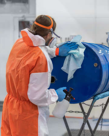 A paint shop worker prepares a blue barrel for painting, close-upの写真素材