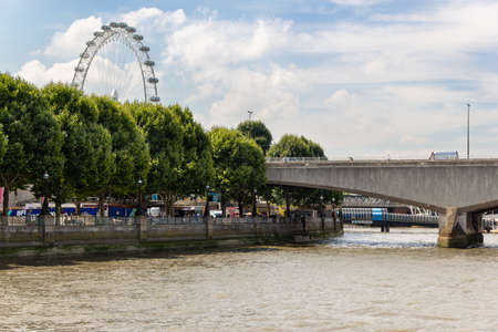 London, UK - 25 July, 2018: Lanscape view on Waterloo Bridge and half of the London Eye Wheel behind the trees.のeditorial素材