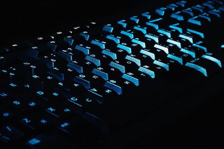 Black keyboard with Russian layout illuminated by blue light. All in black の写真素材