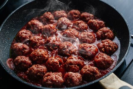 meatballs are cooked in a black frying pan with a hazeの写真素材