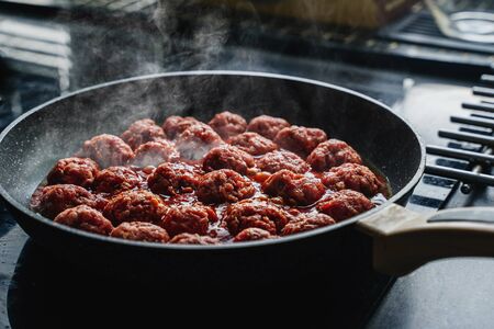 meatballs are cooked in a black frying pan with a hazeの写真素材