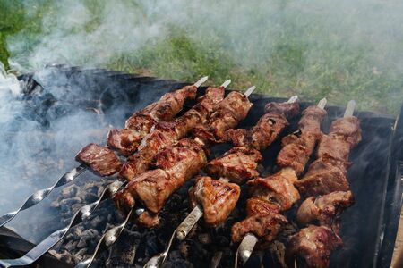 Shish kebab from a pork neck on skewers is prepared on coals in the grillの写真素材