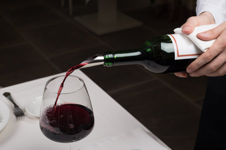 served table restaurant wine being poured into glass, white tablecloth, plates and cutleryの写真素材