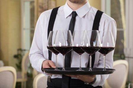 red wine glasses on a tray waiter tray with white wine, a lot of glassesの写真素材
