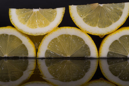 Lemon slices with reflection, black background, isolated, juicy lemons reflection in the dark glassの写真素材