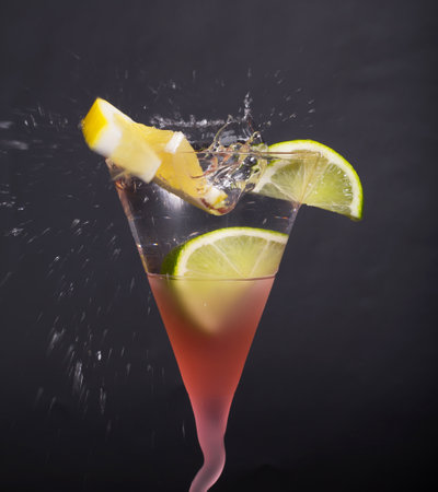 Lemon, lime, splash in martini glass, isolated, splashes on a black background, in red glassの写真素材
