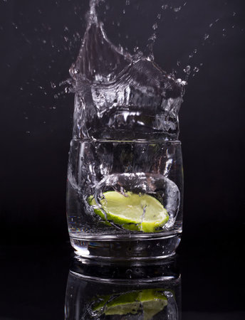 Falling in a glass of lemon, lime, splash on black background, isolated, water dropの写真素材