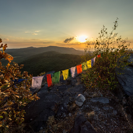 colored flags on top of a mountain at sunset