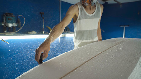 Male surfboard shaper making surfboard in his workshop. Hand shaping from blank.の写真素材