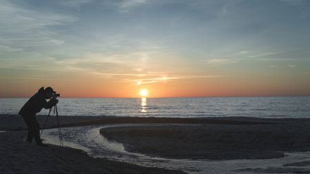 photographer with a tripod on the background of the sea near the streamの写真素材