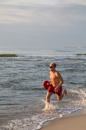 lifeguard on the beach with glasses, with a life buoy, wet sand and sea at sunsetの写真素材
