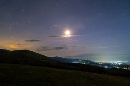 The moon sets in a mountain valley at night