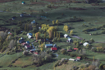 village in mountains close up from above, green meadows and cloudsの写真素材