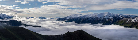 mountain above clouds, with snowy mountain peaks, cloud flows over mountain ridge