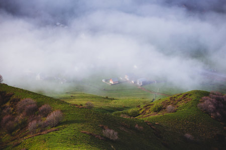 village in the fog of clouds among alpine meadows view from aboveの写真素材