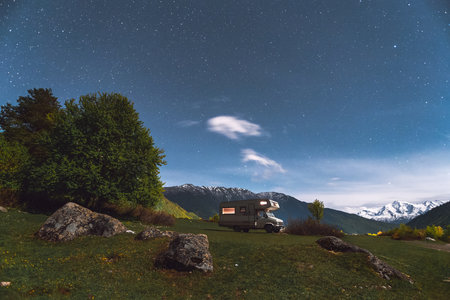 Motorhome camping in the mountains at night, under the starry skyの写真素材