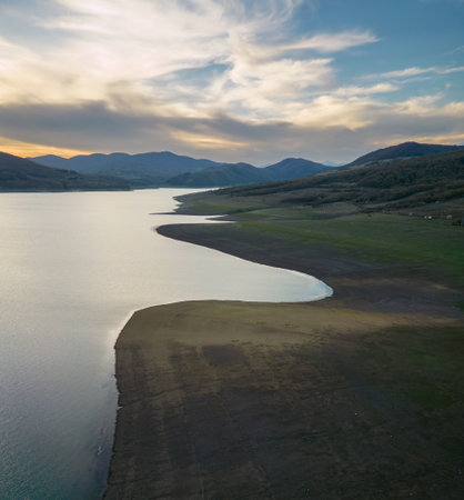 line of the shore of a mountain lake at sunset, green slope shore, aerial viewの写真素材