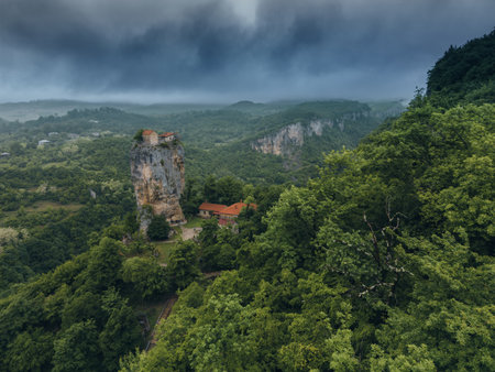 forest covered gorge and house on a rock pillar, cliff house on top, aerial viewの写真素材