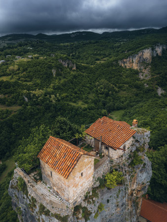 forest covered gorge and house on a rock pillar, cliff house on top, aerial view