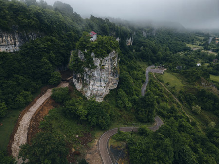 forest covered gorge and house on a rock pillar, cliff house on top, aerial viewの写真素材