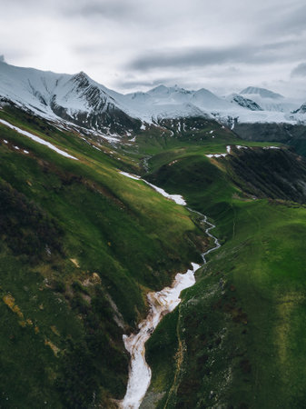 green mountains in snow against snowy peaks, gorge in the mountains, aerial viewの写真素材