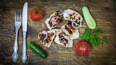 On a wooden tray grilled chicken with vegetables with Cutleryの写真素材