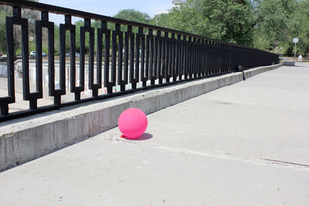 Pink ball on the concrete embankment with a metal fencingの写真素材