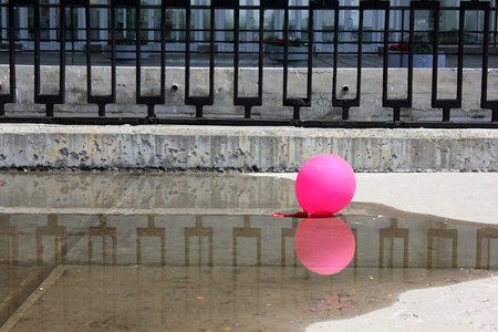 Pink ball on the concrete embankment with a metal fencingの写真素材