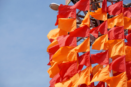 Festive flags of red and orange color on a flagstaffの写真素材