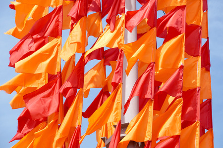 Festive flags of red and orange color on a flagstaffの写真素材