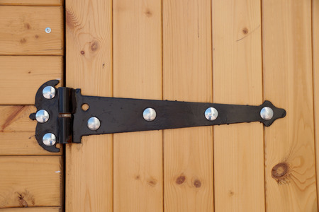 Metal figured door loop on a wall of pavilion with wooden finishing