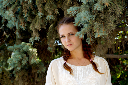 Girl of Slavic appearance against a fir-treeの写真素材