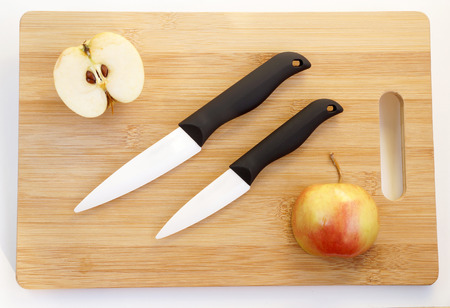 Ceramic knives with black handles on a wooden chopping boardの写真素材