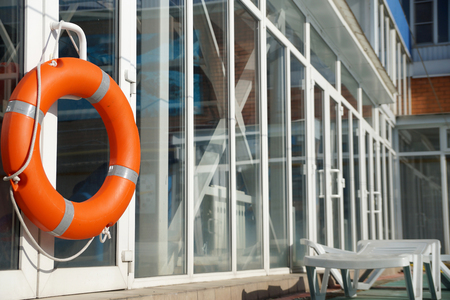 Orange lifebuoy on a wall of a protection of the swimming poolの写真素材