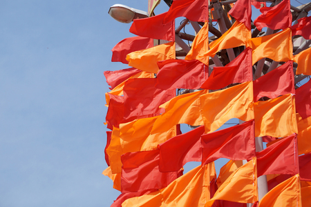 Festive flags of red and orange color on a flagstaffの写真素材