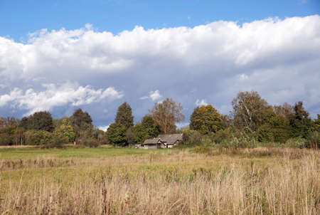Lone standing typical house with a barn in a Belarusian villageの写真素材
